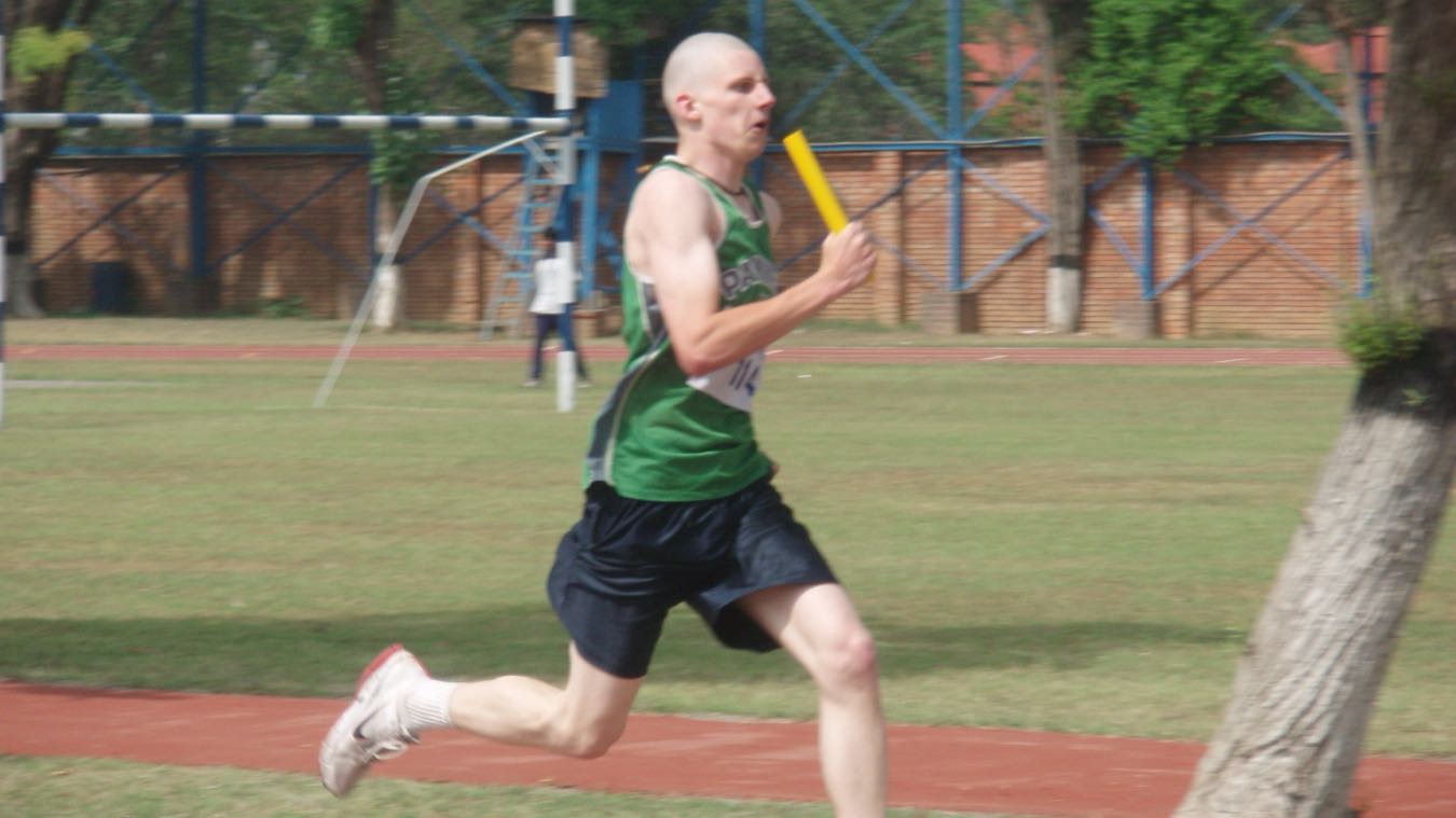 A photo of Sean holding a baton and sprinting in a track meet